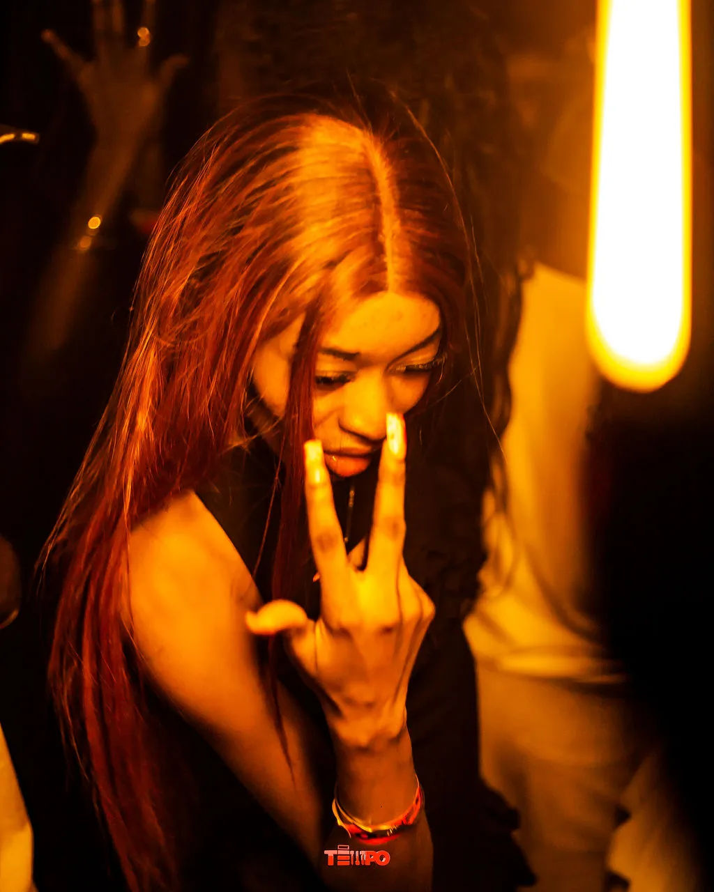 A raver with long red hair throwing up a peace sign
