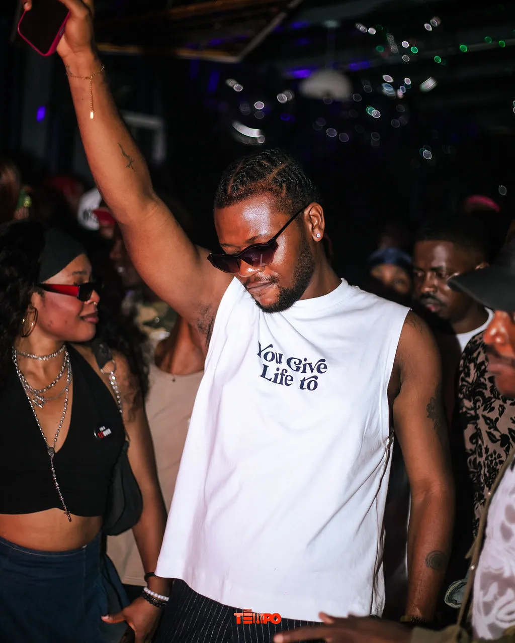 A raver in a white tee dancing with one hand raised